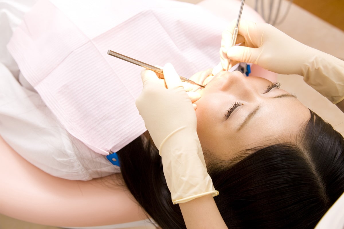 器具を使用して歯の治療をする歯科医