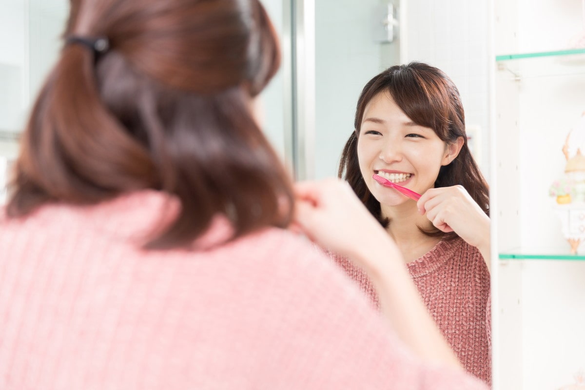 鏡を見ながら歯を磨く女性